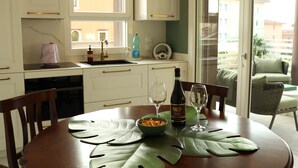 Un coin repas avec une table dressée pour deux personnes, une bouteille de vin et un plat de pâtes.