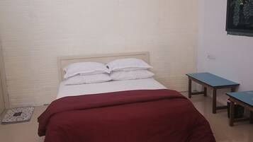 Un dormitorio con una cama, un edredón rojo, dos mesitas pequeñas y un cuadro colgado en la pared.