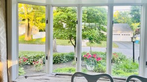 A room with a large sliding glass door leading to a garden with various plants and flowers.