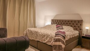 Un dormitorio con una cama grande, una mesita de noche, una lámpara y una silla.