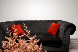 Ein schwarzes Ledersofa mit zwei roten Kissen.