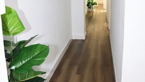 A hallway with wooden flooring, white walls, and two framed artworks. - MODERN AND NEW APARTMENT HUELVA (Huelva)
