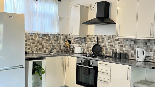 A modern kitchen with white cabinets, a built-in oven, a gas stove, and a refrigerator.