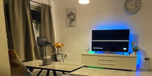Relax in this stylish living room with a flat-screen TV, comfortable chair, and beautiful vase of flowers.