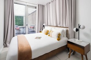 A bedroom with a large bed, a nightstand, and a view of an outdoor area. - Beautiful Studio with Patio in Midtown NYC! #202 (New York)