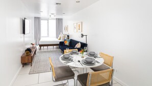 A modern hotel room with a dining area, a bed, and a large window.