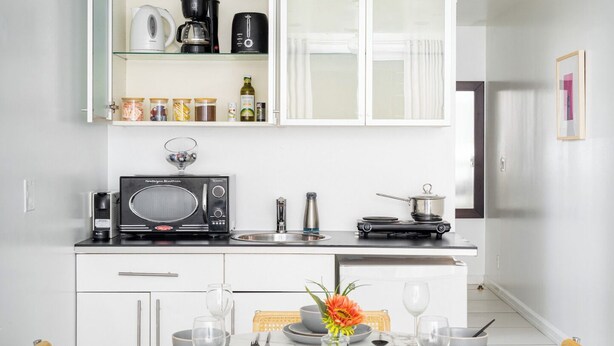 A modern kitchen with white cabinetry, a microwave, a coffee maker, and a gas stove. - Manhattan loft Studio located Midtown NYC! #303 (New York)