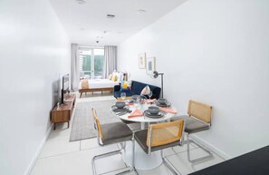 A modern dining area with a round table, chairs, and a sofa in the background. - Chic Midtown Studio with Patio #203 (New York)