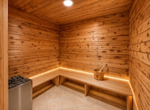 Eine Holzsauna mit BĂ€nken, einem Eimer und einem Holzkohleofen.
