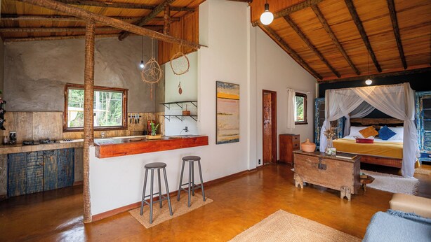 Een rustiek interieur met een keuken, bar en een slaapkamer met hemelbed.