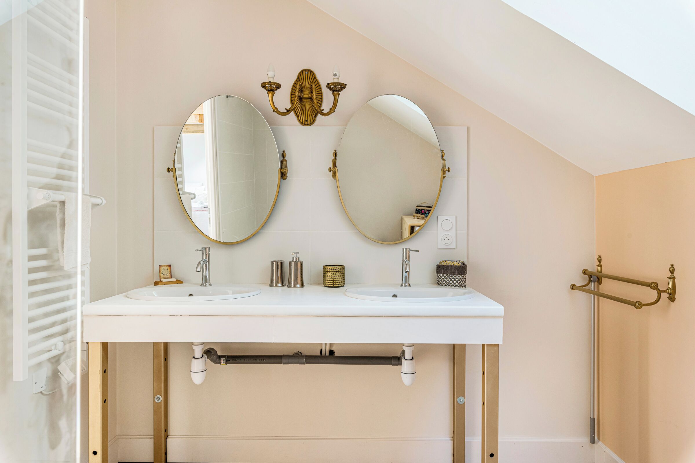 Une salle de bain avec deux lavabos, un porte-serviettes et un espace douche.