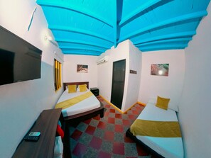 A hotel room with two beds, a desk, a TV, and a check-in counter. - Hotel Acuarela del Rio (Santa Fe de Antioquia)