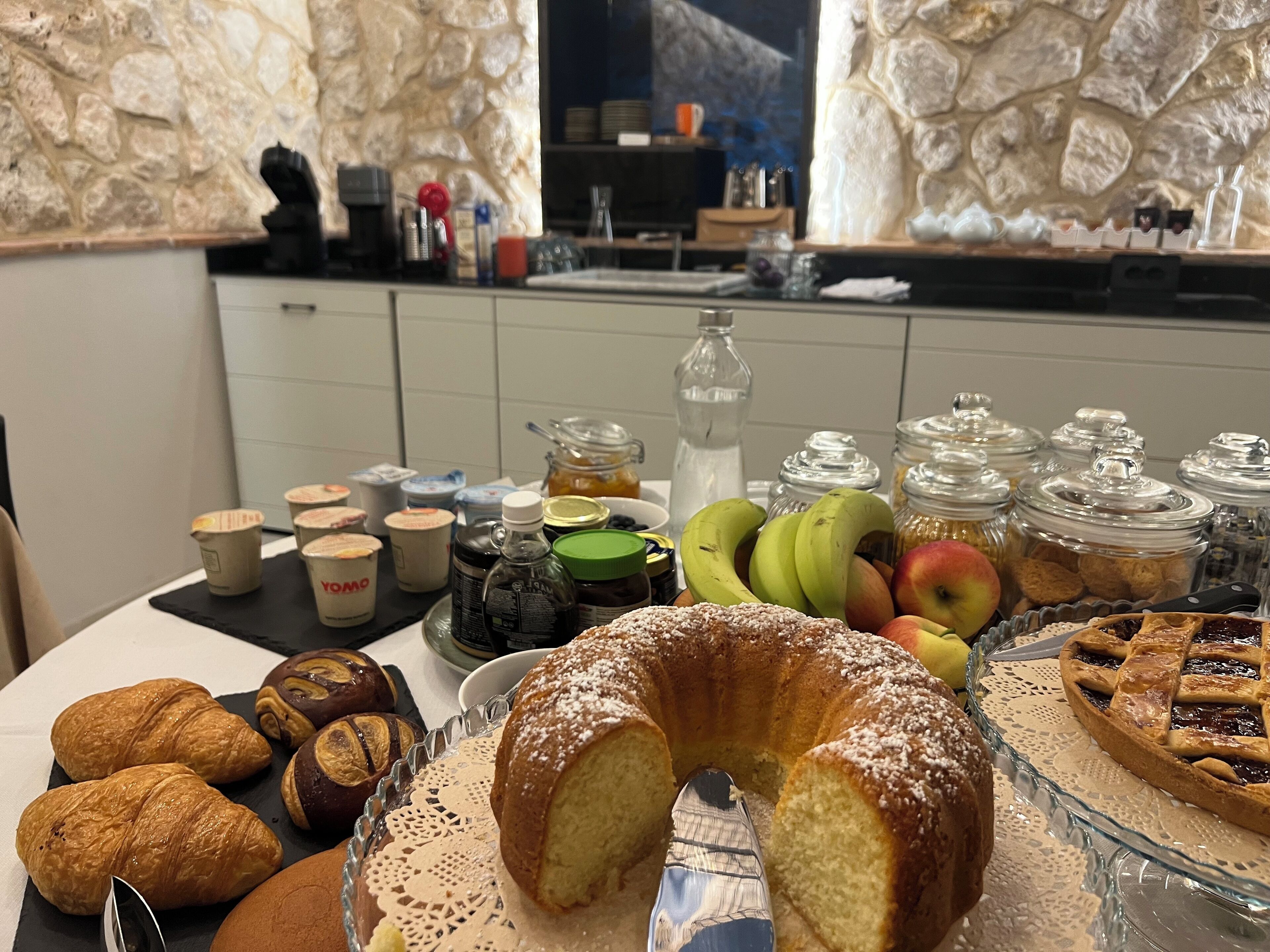 A breakfast buffet with pastries, fruits, and condiments.