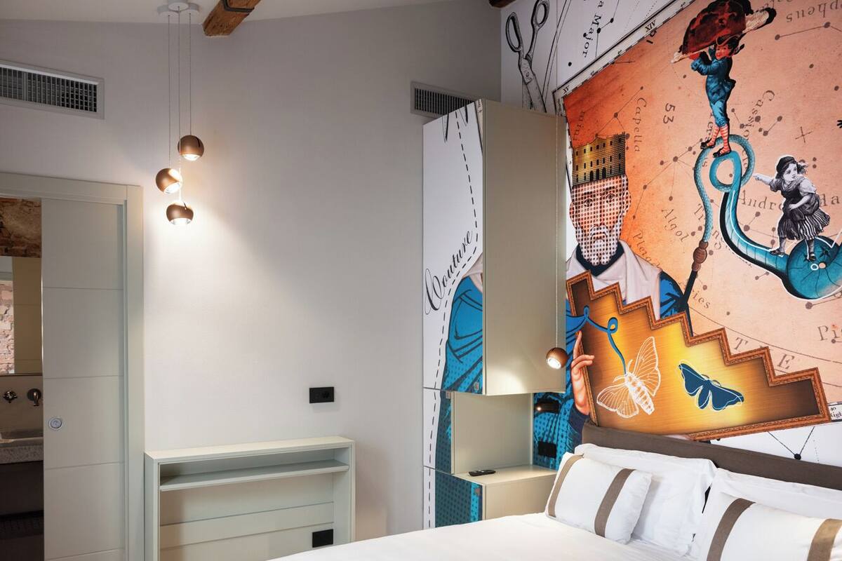 A bedroom with a bed, a nightstand, a dresser, and a wall mural.