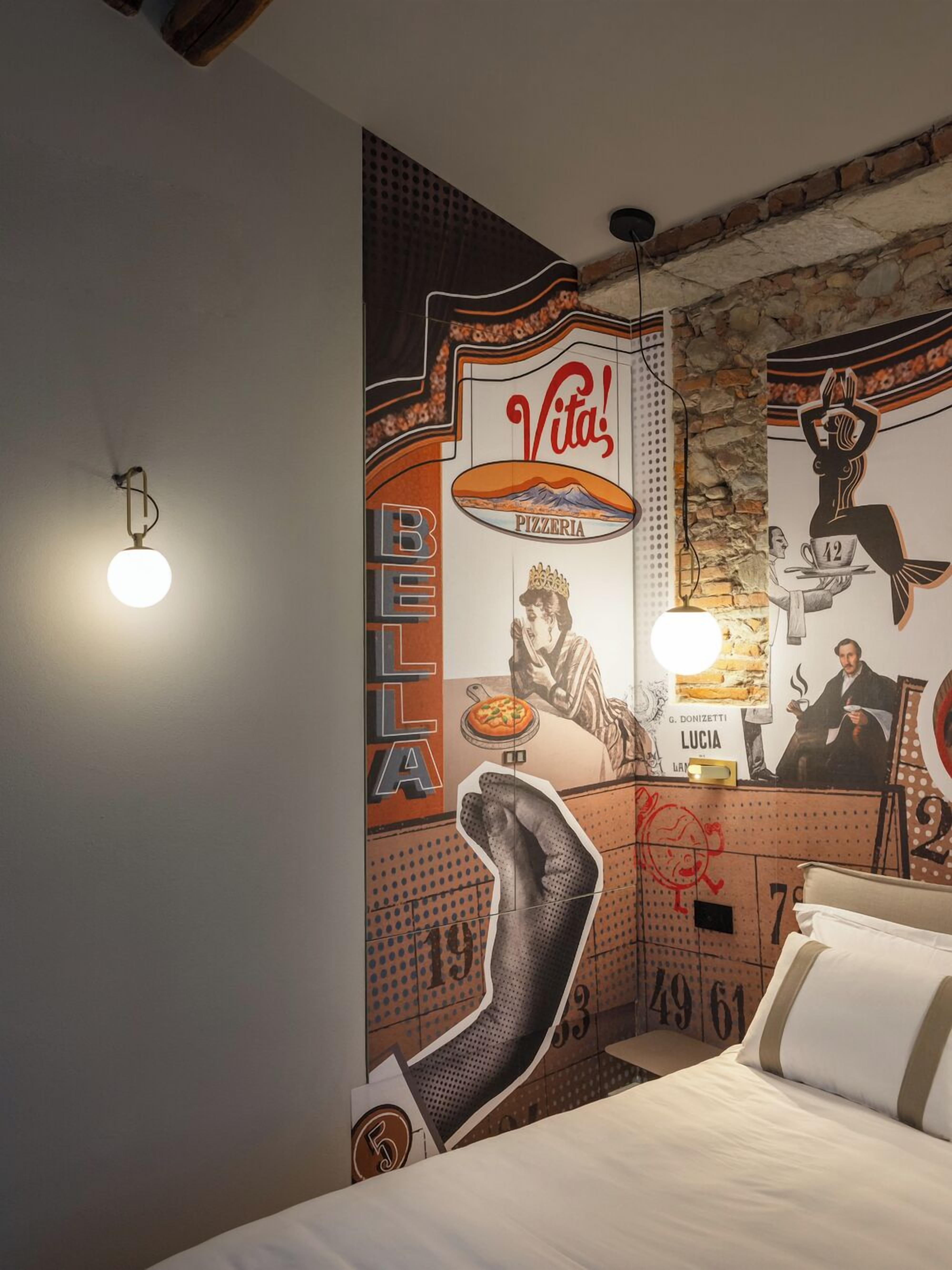 Een hotelkamer met een muurschildering, een bed en een nachtkastje met een lamp.