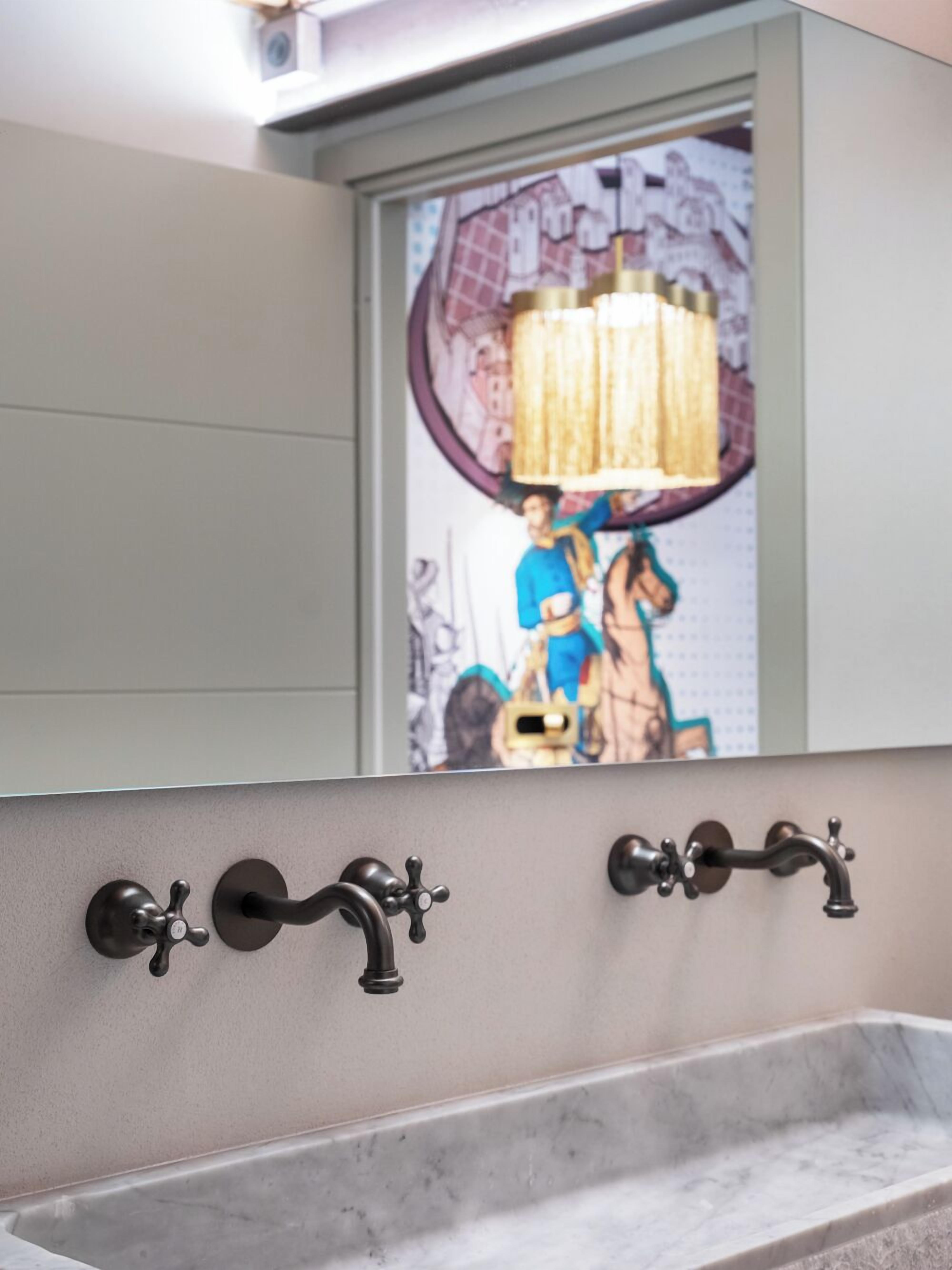 Un bagno con un ampio specchio, un lavabo sospeso e un elegante fioralino.