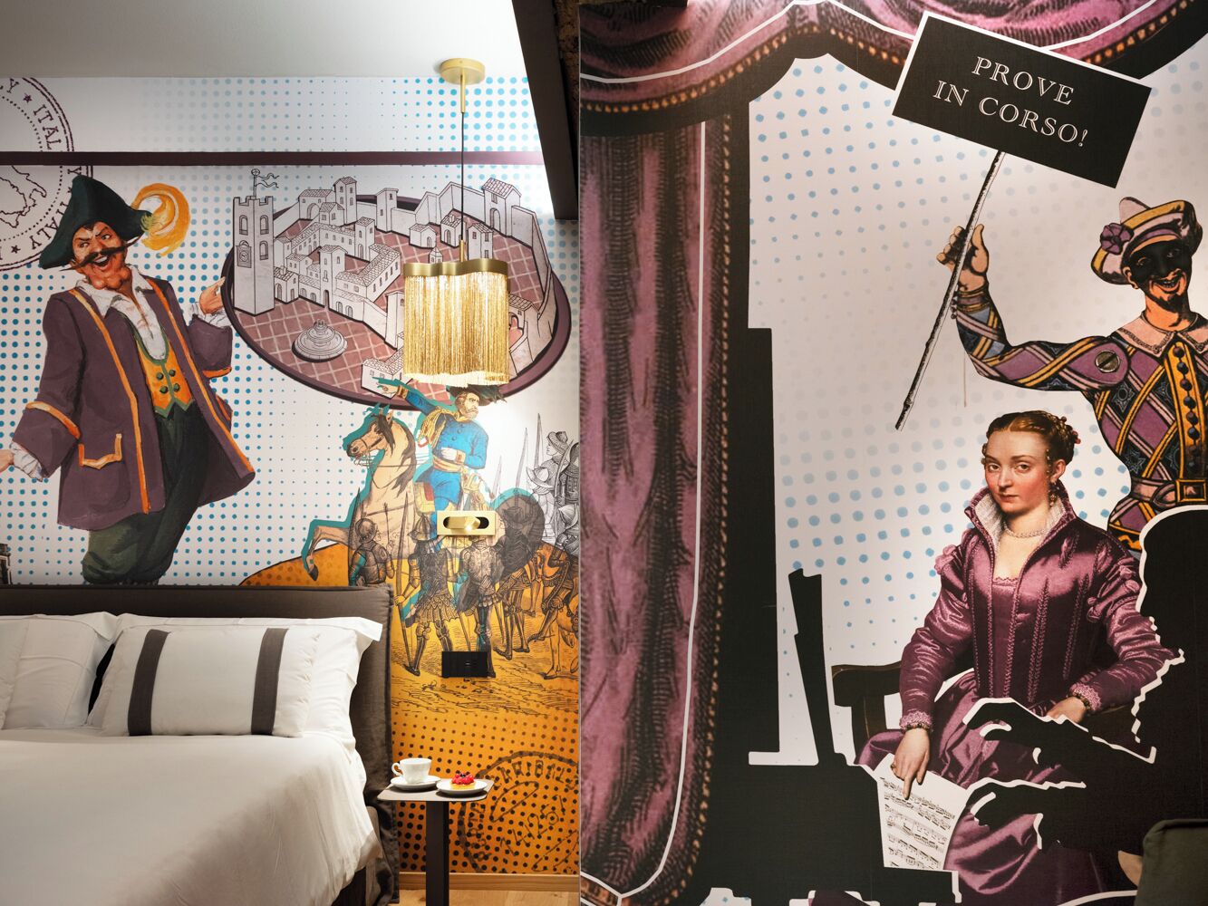 A room with a bed, a mural of historical figures, and a sign that reads "PROVE IN CORSO!".