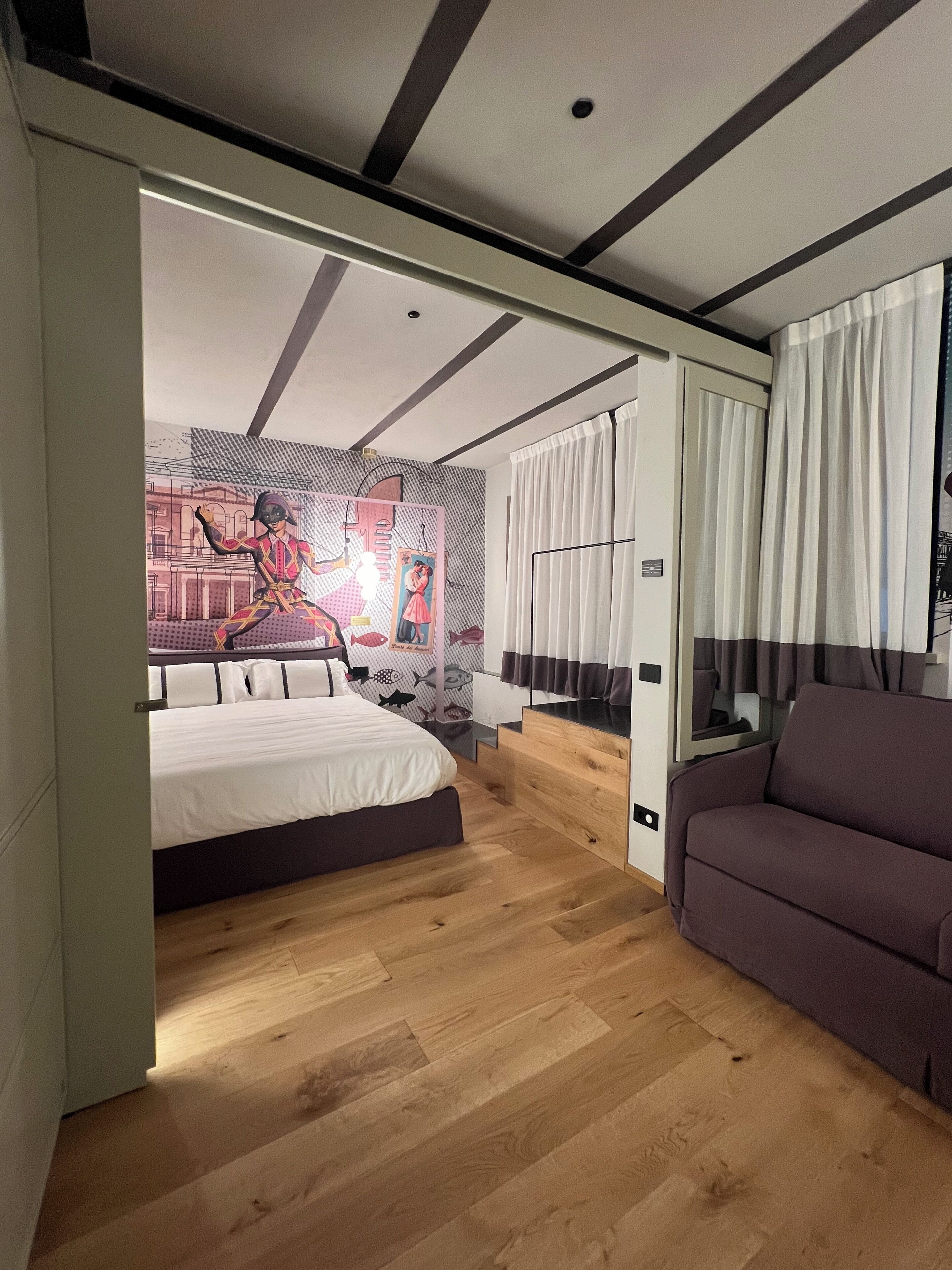 Een moderne slaapkamer met een bed, een bank en een muurschildering.