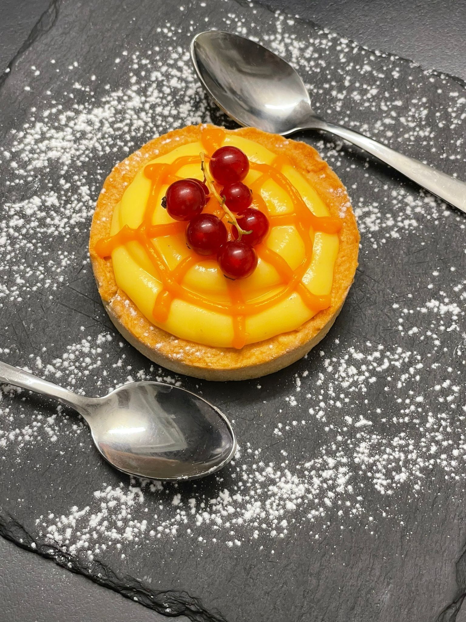 Dessert på skifer med flormelis, serveret med to skeer.