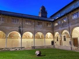 A courtyard with a central fountain, surrounded by arches and a building with classical architecture.