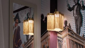 A hotel room with a bed, a large wall mural, and two hanging lamps. - Pietrasanta Ai Teatri (Pietrasanta)