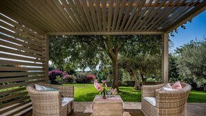 An outdoor patio area with wicker furniture, a stone table, and a pergola overhead. - Villa Ramunna 6, Emma Villas (Rosolini)