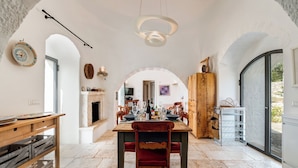 A spacious dining area with a wooden table and chairs, a fireplace, and a view through an archway.
