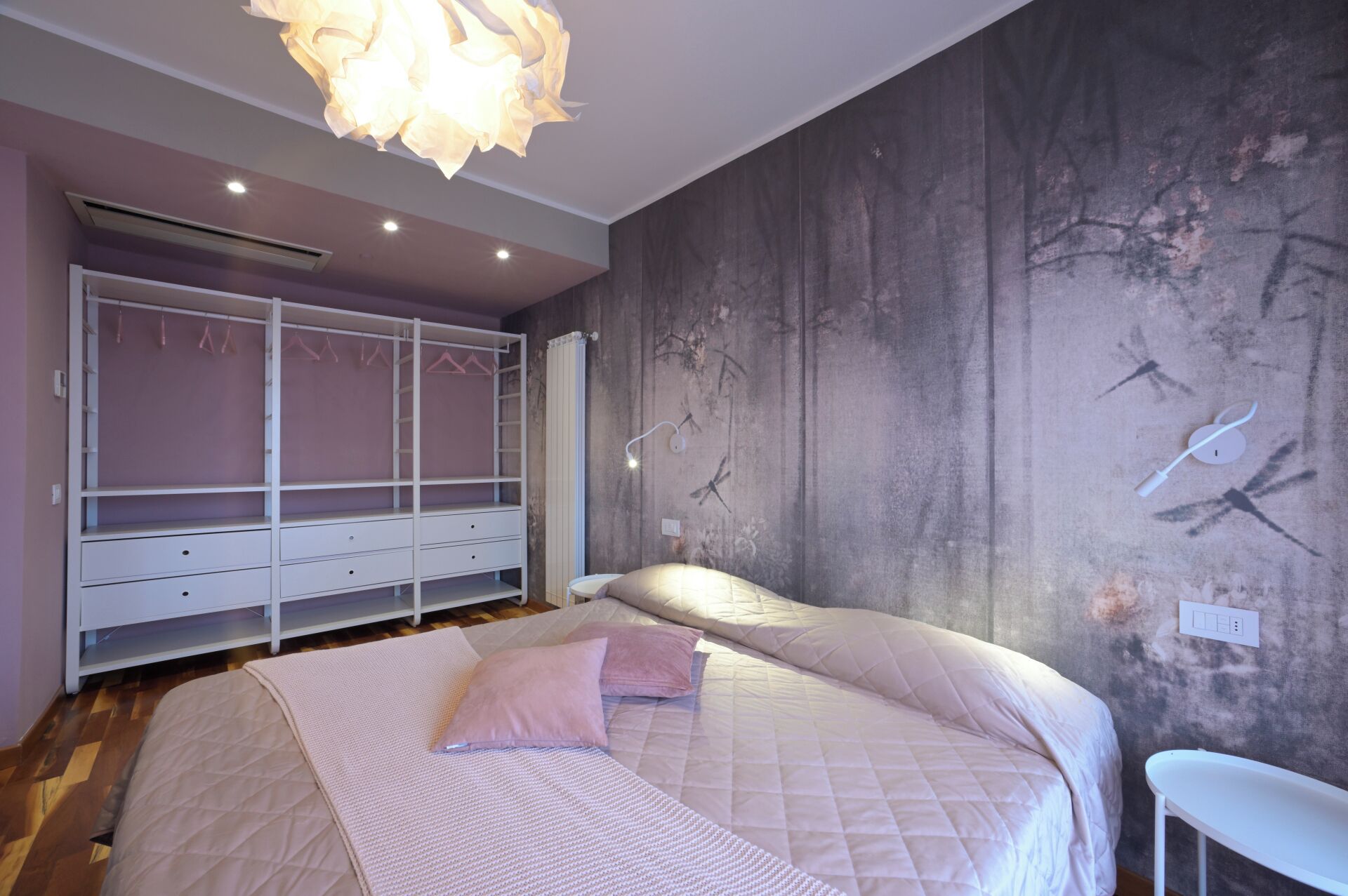 Een slaapkamer met een bed, een kledingkast en een muur met een natuurdecoratie.