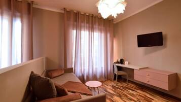 Habitación de hotel moderna con cama, escritorio, silla, una mesita y televisor en la pared.