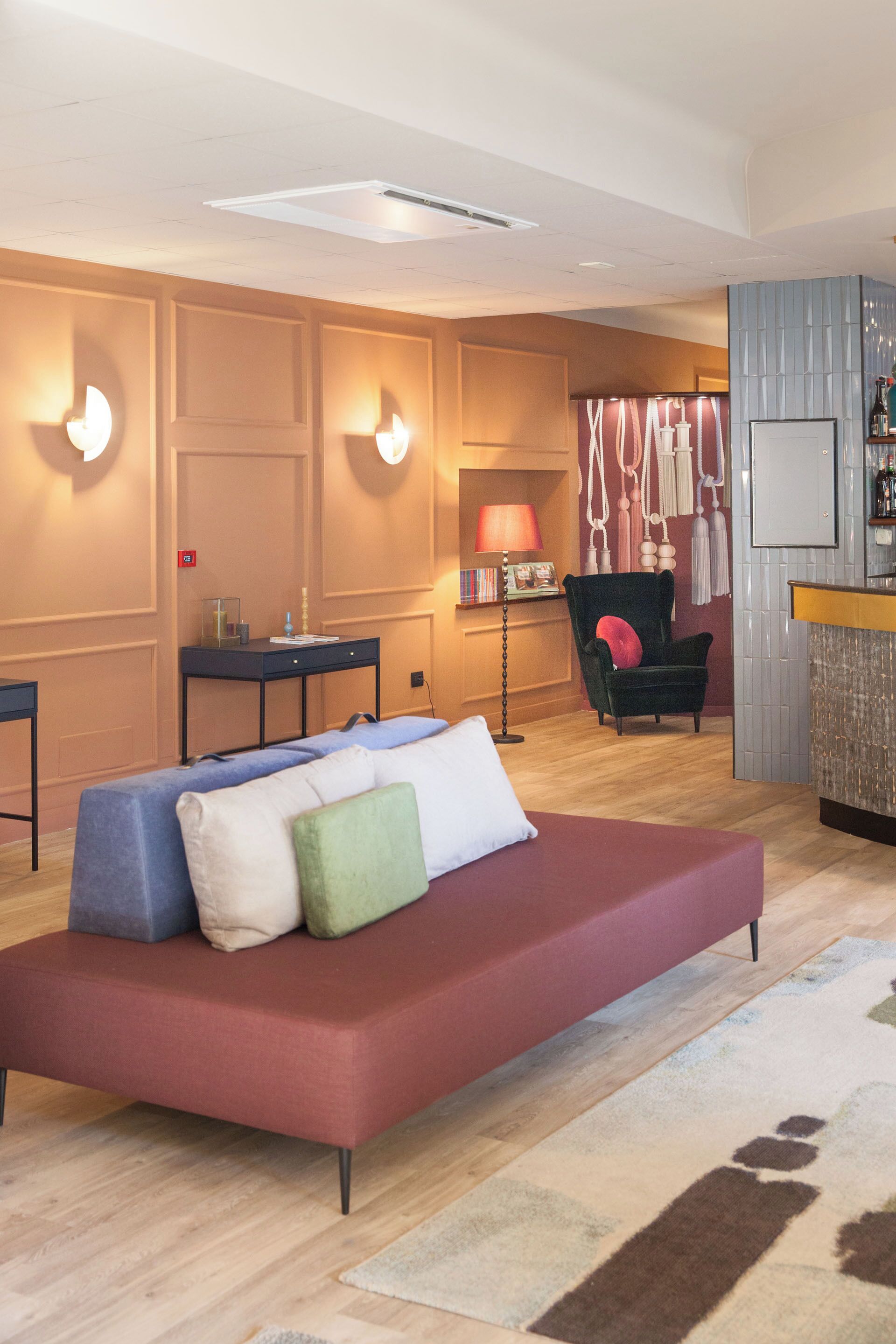 Une chambre d’hôtel moderne équipée d’un canapé, d’un bureau, d’une chaise, d’une lampe et d’un coin bar.