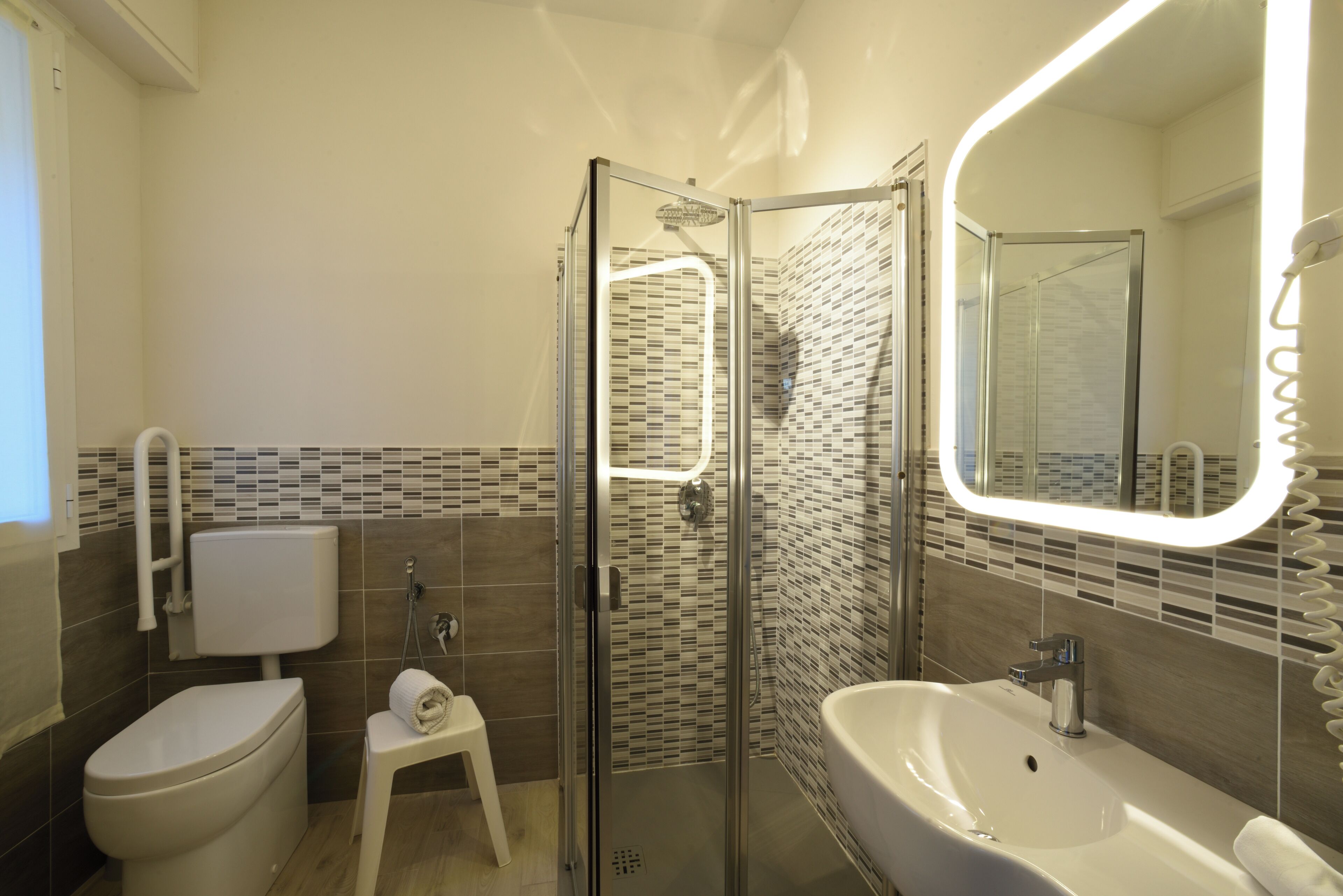 Een moderne badkamer met een douchecabine van glas, een wit wastafelmeubel en een toilet.