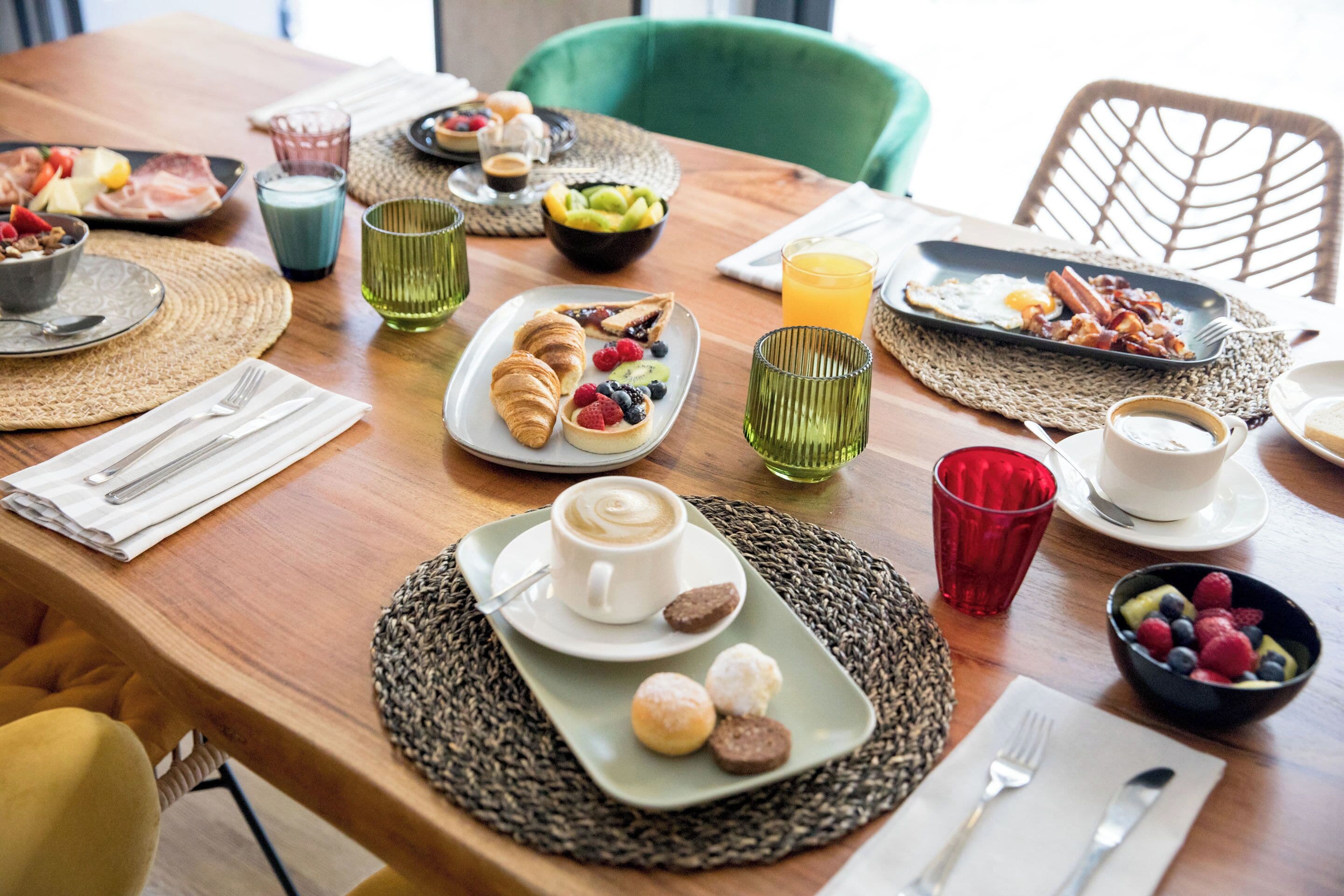 A breakfast table with various dishes, drinks, and utensils.