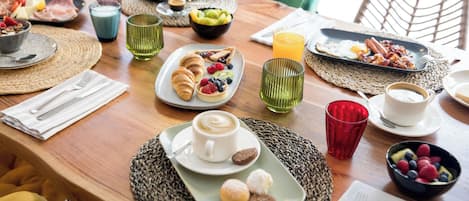 A breakfast table with various dishes, drinks, and utensils.