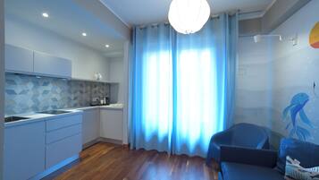 Eine moderne Küche mit geometrischer Spritzschutz, ein Essbereich mit blauem Sofa und ein großes Fenster mit blauen Vorhängen.