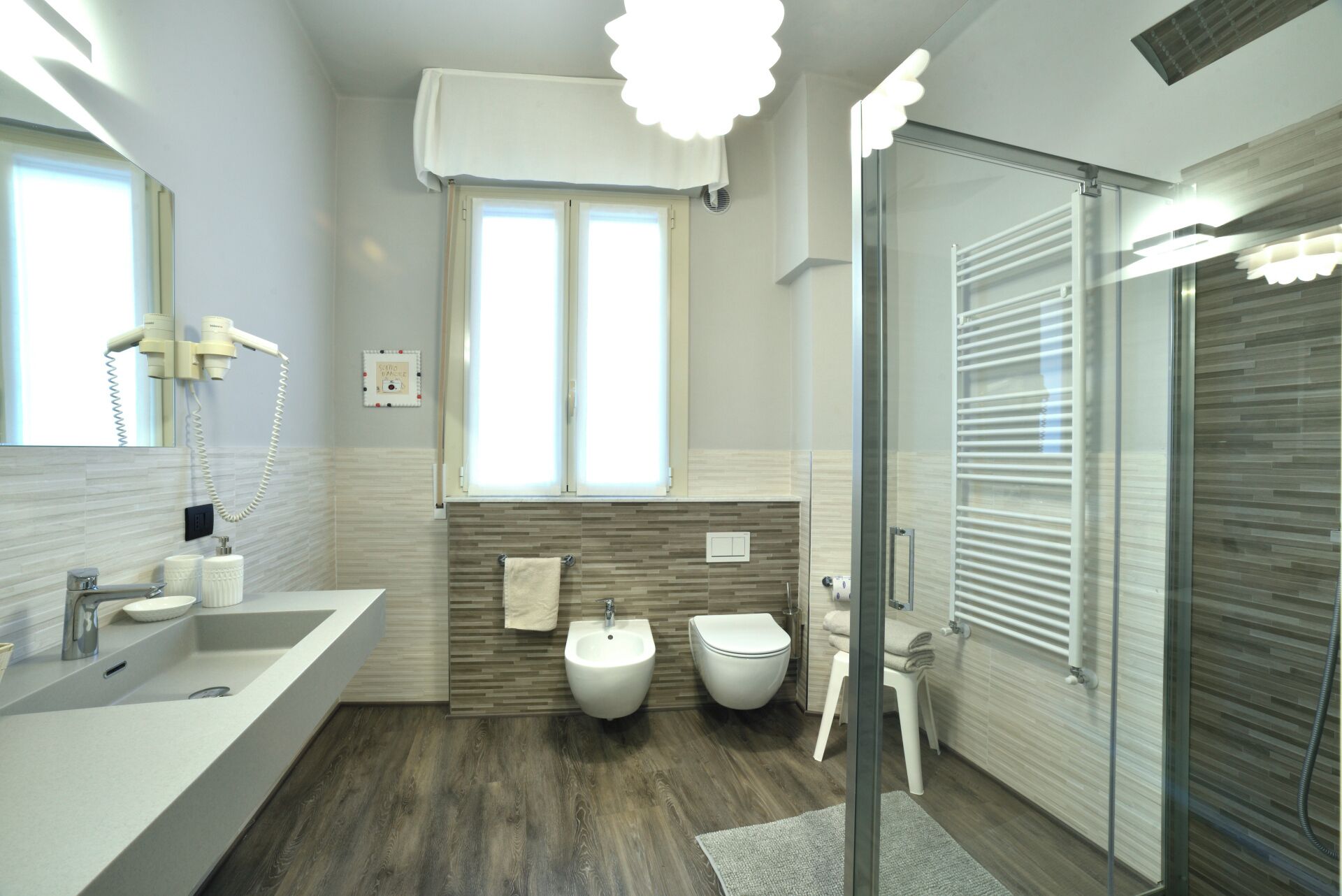 Un baño moderno con un lavamanos grande, bidé y cabina de ducha de vidrio.