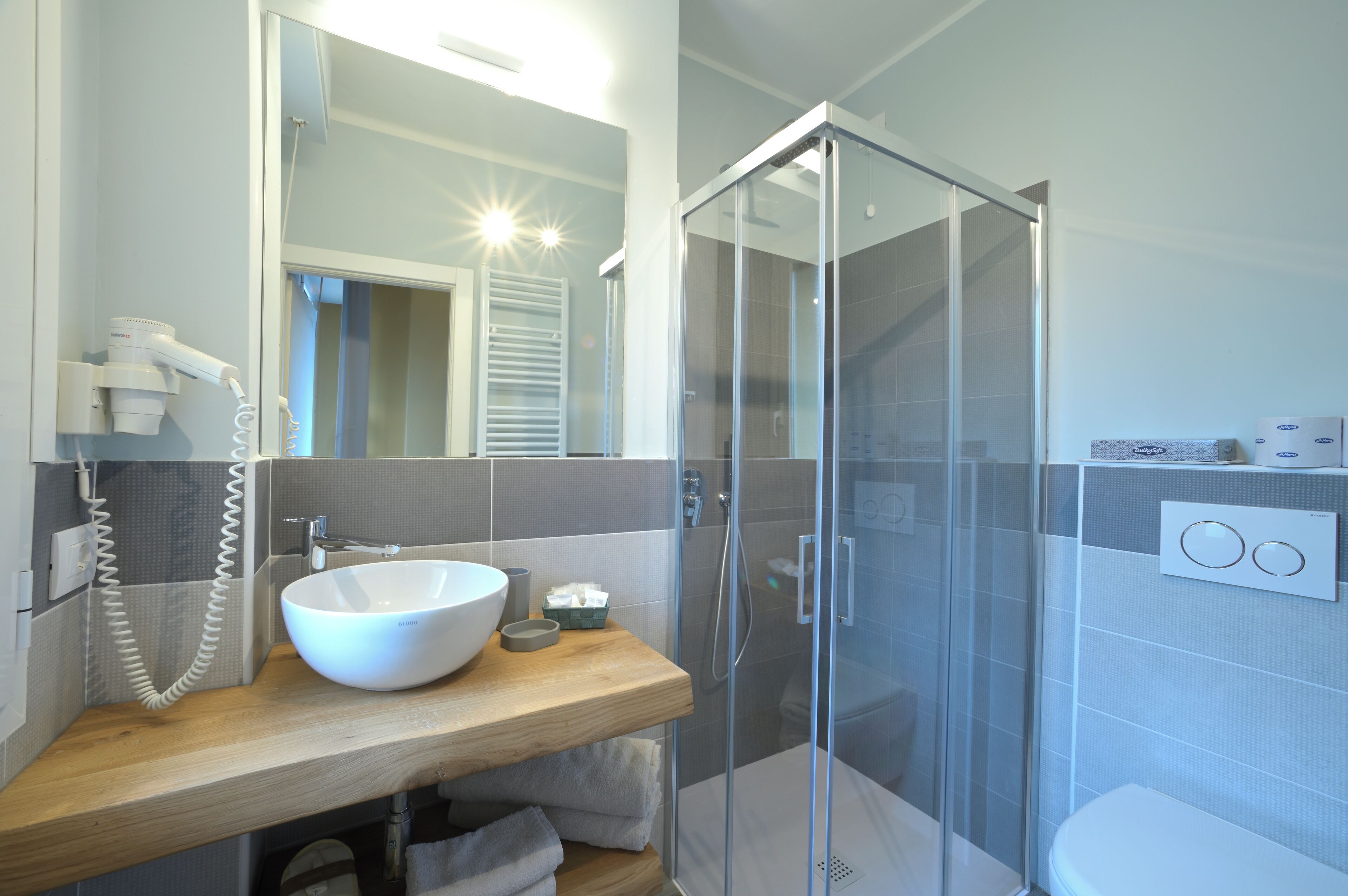 A modern bathroom with a glass-enclosed shower, a wooden vanity with a white sink, and a mirror above the sink.