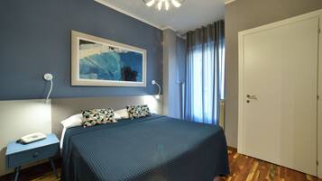 A bedroom with a bed, a nightstand, a telephone, and a door.