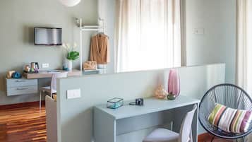 Camera da letto moderna con scrivania, sedia, letto, televisore e finestra con tende.