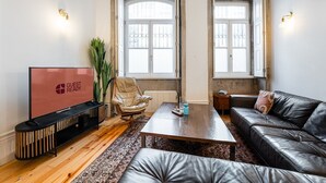 Ein modernes Wohnzimmer mit Flachbildfernseher, Ledersofa, Holztisch und einem großen Fenster mit Blick.