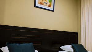 A hotel room with two beds, each with white linens and dark headboards. There is a framed picture on the wall above the beds. - Di Costa Hoteles (Piura)