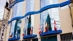 A hotel named "Di Costa" with a modern facade, multiple flags, and a balcony. - Di Costa Hoteles (Piura)