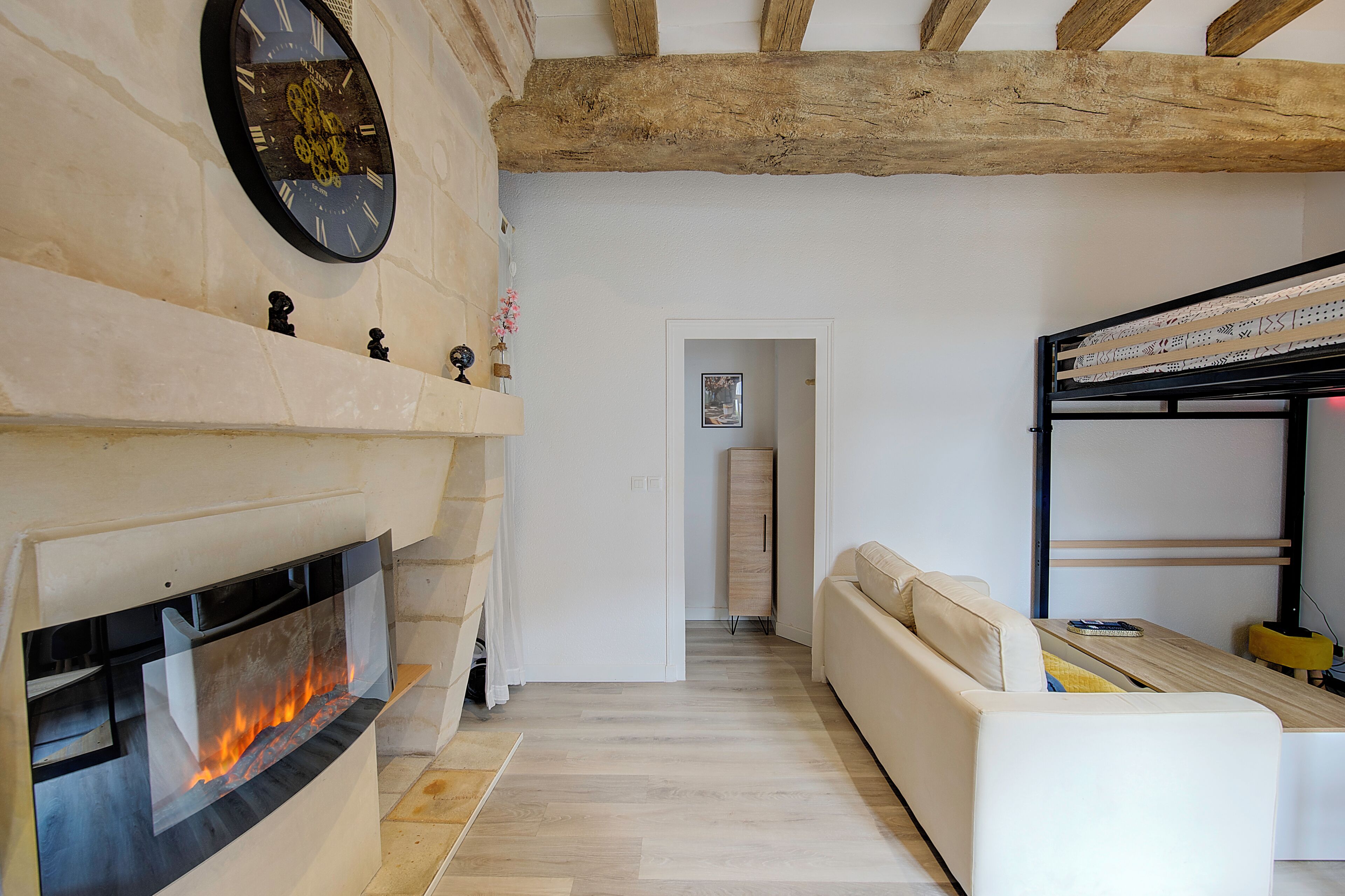 A living room with a fireplace, a sofa, and a wooden ceiling.