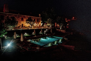 Un edificio de piedra con piscina, mobiliario exterior y un puente.