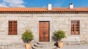 Un edificio de piedra con techo de tejas, una puerta de madera y dos ventanas con marcos de madera. Un letrero sobre la puerta dice "CASA DO BOCO".