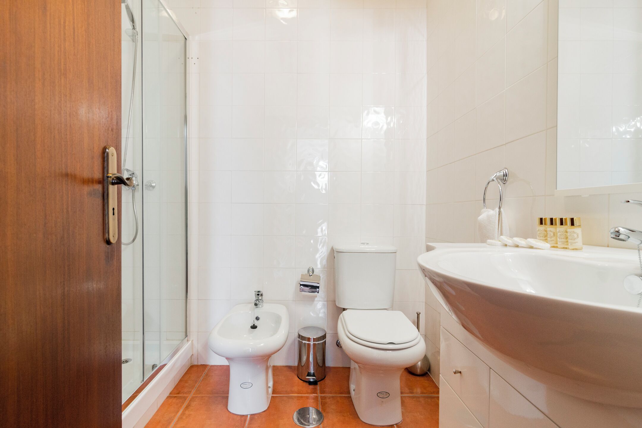 A bathroom with a shower, bidet, toilet, and sink.