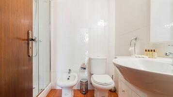 A bathroom with a shower, bidet, toilet, and sink.