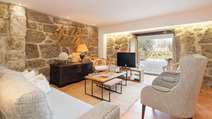Una sala de estar con paredes de piedra, un sofá, una mesa de centro, un televisor y un sillón.