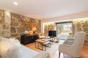 Una sala de estar con paredes de piedra, un sofá, una mesa de centro, un televisor y un sillón.