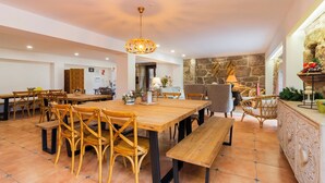 Un comedor espacioso con mesas y sillas de madera, una pared de acento de piedra y una lámpara colgante.