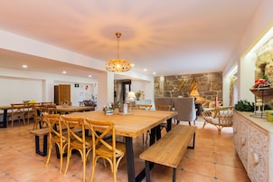 Un comedor espacioso con mesas y sillas de madera, una pared de acento de piedra y una lámpara colgante.